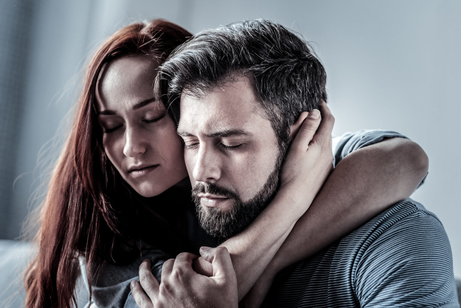 Redhead satisfied woman hugging her husband closing her eyes.